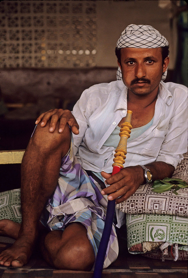 A patron chewing Khat leaves with a water pipe  in  a tea shop. Sanaa, Yemen, :  DAILY LIFE; The Rich, the Poor & the Others : Viviane Moos |  Documentary Photographer