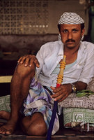 A cafe patron smoking a water-pipe and chewing khat, Yemen - © Viviane Moos