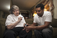 Dr. Nigel Verasami, on his monthly home visit, discovers that Savina, who is diabetic and can't walk, has not been using her blood sugar monitor correctly. - © Viviane Moos